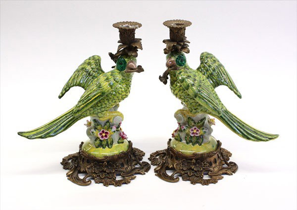 Continental earthenware parrots: Pair of late 19th century Continental polychromed decorated earthenware parrots on a naturalistic ground with applied flowers surmounted by gilt metal acanthus candle holders on a Rococo style gilt me