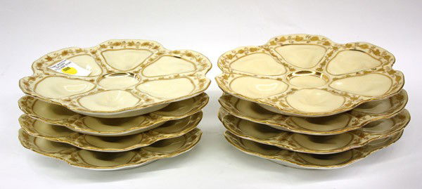 Limoges oyster plates: (Lot of 8) Set of A.K Limoges, France oyster plates, each having eight sections flanked with raised gilt floral and vine detail surrounding a central condiment reservoir, marked with a red overglaze m
