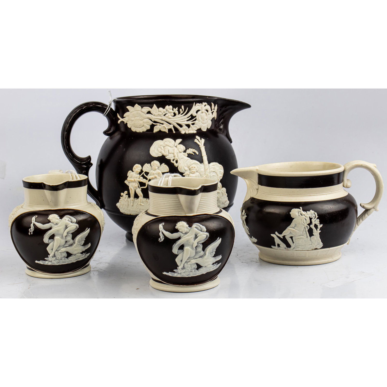 (lot of 4) Parian relief decorated pitchers: the: (lot of 4) Parian relief decorated pitchers: the largest marked "Wilson", the tallest 5.25"h