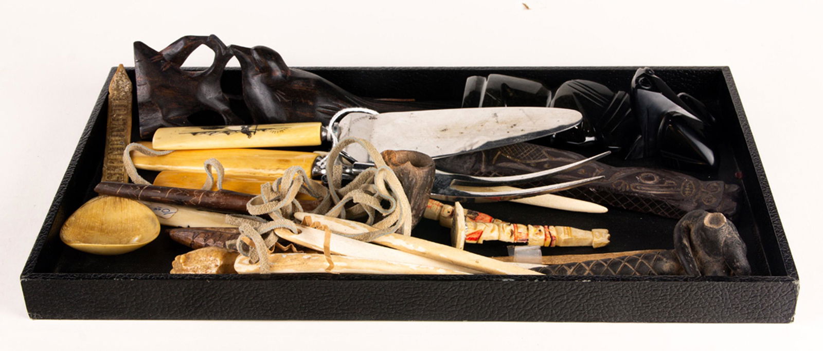 Assembled group of stone, bone and wood items,: Assembled group of stone, bone and wood items, including (2) scrimshaw handled serving utensils; a scrimshaw handle; bone needles; (3) stone carvings; figural pipe; (2) miniature bone totems; horn spo