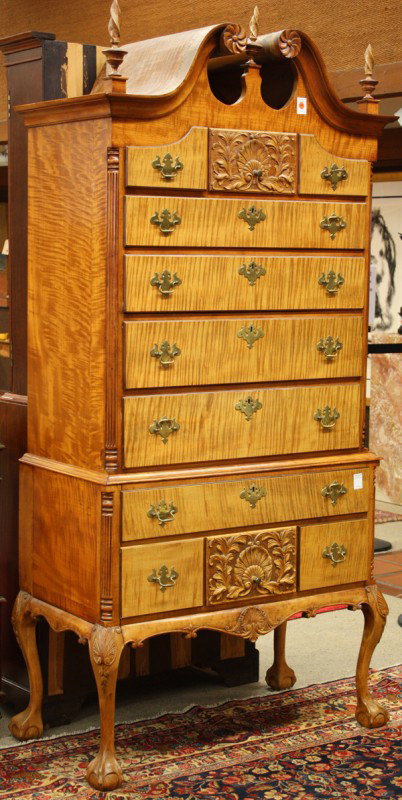 Queen Anne style highboy: Queen Anne style Centennial highboy circa 1860, executed in tiger maple veneer, the top having a broken pediment with carved rosettes flanked with turned finials, above the graduated drawer case havin