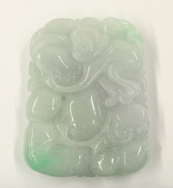 Chinese Jade Toggle/Pendant: Chinese jade toggle/large pendant, carved in relief with a monkey grasping a large peach issuing from a fruiting spray, reversed by a bat and large lingzhi sprig, the pale green stone splashed with tw
