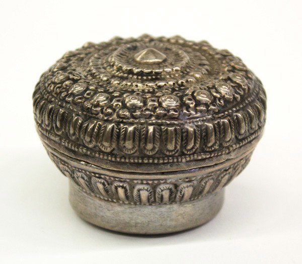 Southeast Asian Repousse Silver Box: Southeast Asian repousse silver circular covered container, the lid decorated with small floral blossoms encircling a stylized floral roundel to the center, the body hammered with a petal pattern and 