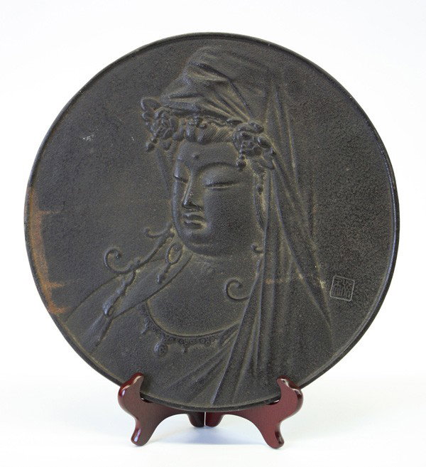 Japanese Iron Buddhist Plaque, Kannon: Japanese circular iron buddhist plaque, well cast in relief with a portrait of Kannon, the 'Deity of Mercy' with downcast eyes and full lips framed by a cowl partially obscuring the coiffure and numer