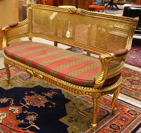 Louis XVI style settee: Louis XVI style settee, the rectangular back continuing to the bowed arms each having cane panels, and rising on carved cabriole legs, 36''h x 59''w