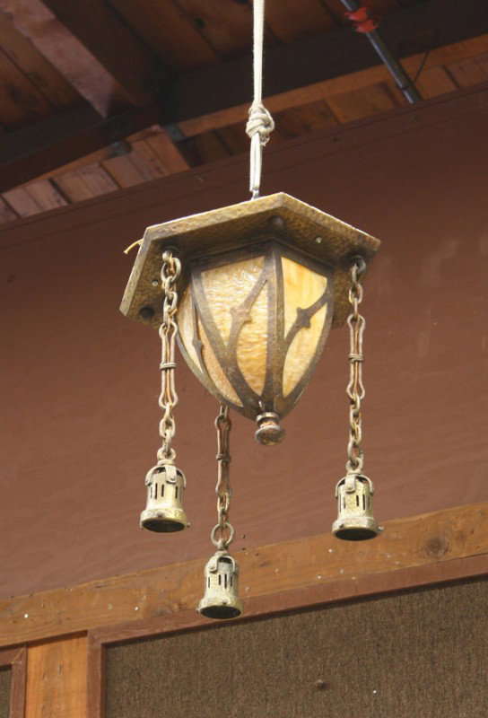 Arts and Crafts hanging fixture: Arts and Crafts hammered light fixture circa 1915,the central light with a tapering form having slag glass panels, flanked by three hanging pulled feather art glass shades, (one shade restored) 23''h 