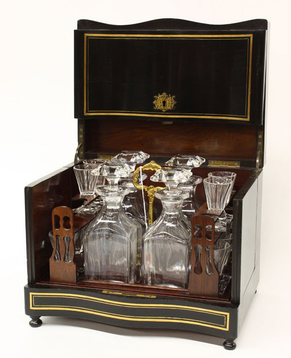 French tantalus ebonized boulle case circa 1890: French tantalus having an ebonized brass inlay case, circa 1890, rising on bun feet with removable rosewood interior opening to reveal 4 crystal decanters and 12 cordial crystal glasses, 10.25''h x 12