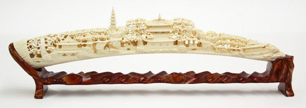 Chinese Pierced Ivory Tusk: Chinese reticulated ivory tusk, the contoured segment with two sides carved and pierced with a village landscape centered by a large two tier pavilion bracketed by stylized trees, rockwork and villas 