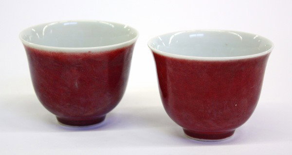 Chinese Ox Blood Glazed Porcelain Cups: Pair of Chinese sang de bouef glazed porcelain cups, each of inverted bell form coated with a mottled deep red glaze to the exterior, the recessed base with an underglaze cobalt blue mark 'Yongle Tang