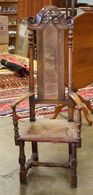 Continental Renaissance Style hall chair: Continental oak renaissance style hall armchair, circa 1800, with a carved crest terminating with scrolls, below a woven wicker seat back, flanked by turned stiles, below a leather seat, supported by 