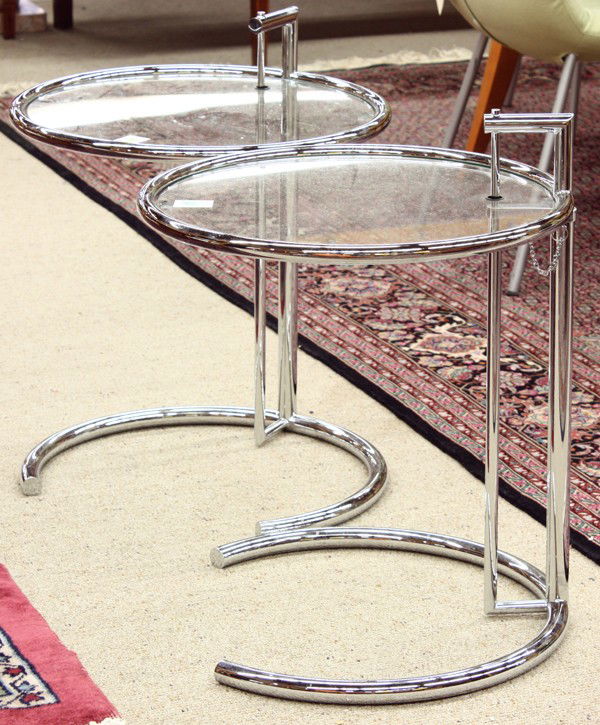 Eileen Gray E1027 tables: Pair of Eileen Gray adjustable tables, each executed in tubular steel and having a glass top, 25''h x 19.5''w