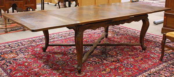 Louis XV style dining suite: (lot of 11) Louis XV style dining suite, the draw leaf oak table having a parquet top above a scalloped apron with relief carved floral reserves and rising on carved cabriole legs conjoined with an X