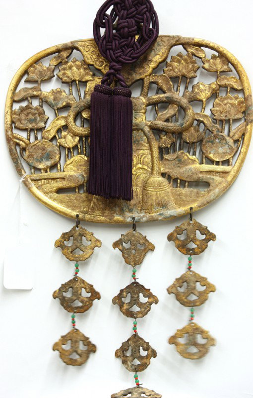 Japanese Gilt Bronze Keman (Buddhist Decoration): Japanese gilt bronze keman (Buddhist altar decoration), cast with a floral-etched plaque overlaid by tasseled cords, all silhouetted against a reticulated design of a lotus pond within the fan-shaped 