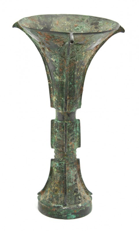 Chinese Archaic Bronze Vessel, Shang/Western Zhou: Chinese archaic bronze gu-form vessel, late Shang/early Zhou period, the trumpet neck cast with leiwen-accented stiff leaves centered around the notched flanges, all above the central lobe featuring l