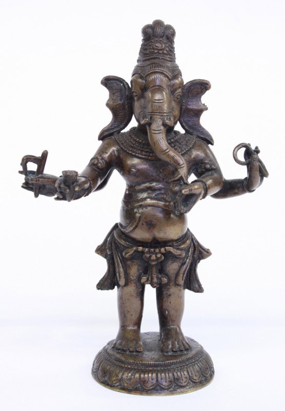 East Indian Metal Ganesha: East Indian patinated bronze figure of Ganesha, the elephant-headed deity with a human torso standing on a lotus pedestal, his four arms holding attributes such as a noose, sweetmeat jar, tusk and a g