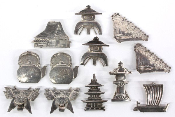 Japanese Silver Place Card Holders: (Lot of 12) Group of Japanese silver place-card holders, fashioned in various shapes including: stone lanterns (2), samurai helmets (2), Mount Fuji (2), tea kettle (2), pagoda, farm house, temple lant