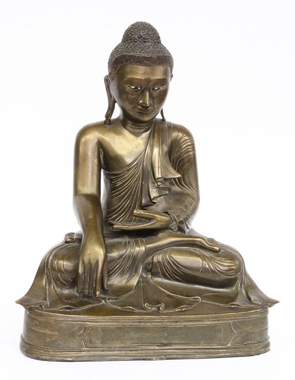 Southeast Asian Bronze Buddha: Southeast Asian patinated bronze figure of the historical Buddha, cast with sharp facial features heightened by inlaid eyes, the body draped in monastic robes cascading into rhythmic folds and with hi