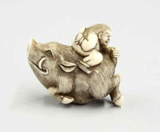 Japanese Figural Netsuke: Japanese ivory figural netsuke, Taisho/Early Showa period, carved and incised as a hunter attempting to cut the tail of a boar while riding on the back of the massive creature, the details heightened 