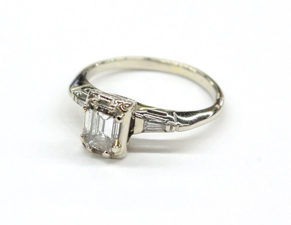 emerald cut diamond ring white gold: Diamond ring; mounted in 14k white gold, set with (1) emerald cut diamond weighing 0.73 ct, accented by (2) diamond baguettes. Total ring weight 2.5 grams
