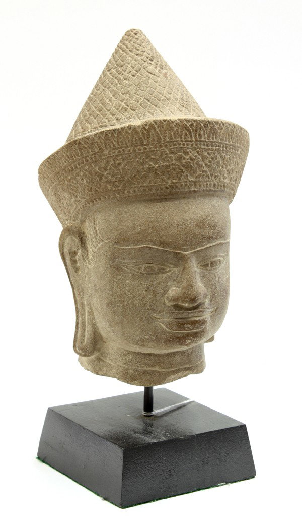 Southeast Asian Khmer-style stone head: Southeast Asian Khmer-style stone head, Angkor Wat style, the crisply defined facial features framed by an ornate headdress, 12''h; with a black lacquered wood stand