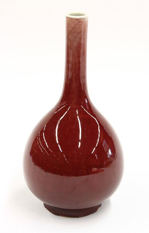 Chinese Sang De Boeuf Stick Neck Vase: Chinese ox blood glazed porcelain stick neck vase, the slender cylindrical neck set above a pear shaped body raised on a short recessed base, the exterior coated with a red crackle glaze thinning at t