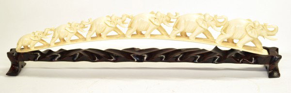 Ivory Elephant Bridge: Ivory tusk carved with six elephants, the animals of graduated size and parading in single file on an arched 'bridge', 13.5''l; with wooden stand