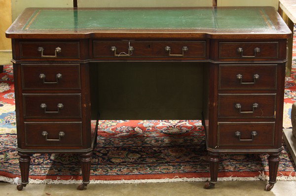 Edwardian kneehole desk: Edwardian kneehole desk, having an gilt and embossed leather writing surface above the mahogany case and rising on fluted legs terminating on casters, 29''h x 48''w x 23''d