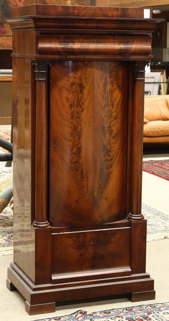 Classical libation cabinet: Classical flame mahogany libation cabinet circa 1830, the ogee molded crest above a single drawer supported with full carved Corinthian pilasters centering the bowed single door opening to reveal a st