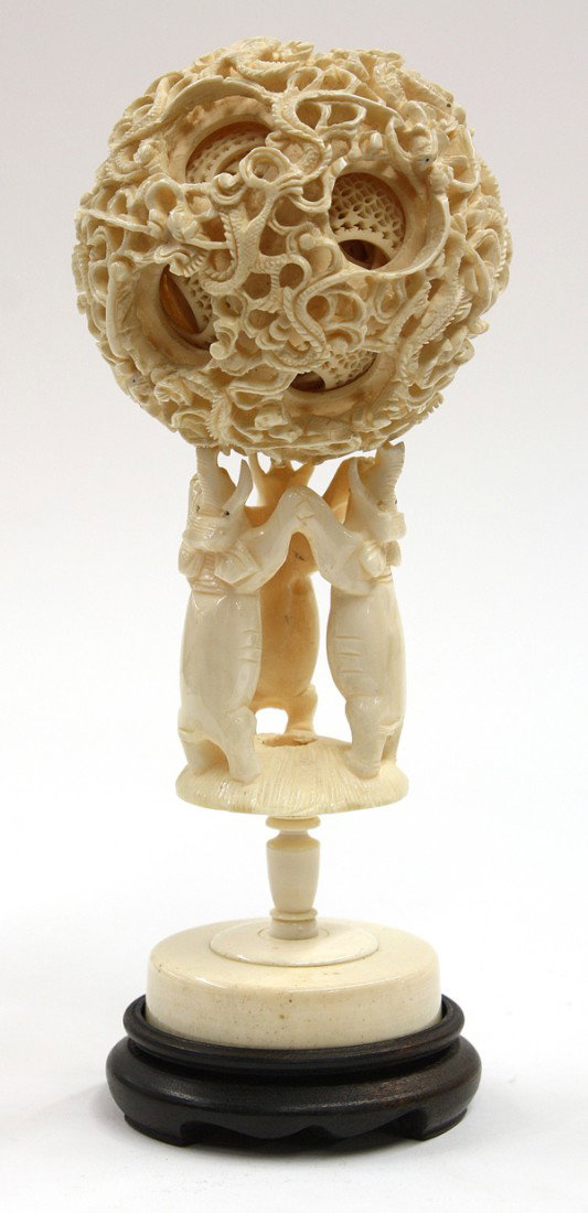 Chinese Ivory Puzzle Ball/Elephant Stand: Chinese ivory puzzle ball and stand, the ball carved with entwined dragons amid cloud scrolls enclosing seven or more pierced layers (minor chips and cracks); together with a stand formed by three ele