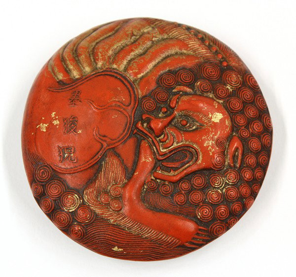 Chinese Cinnabar Ink Cake: Chinese gilt accented cinnabar ink cake, of circular form molded with a roaring fu-lion with its head framed by tight curls and issuing a flame bounding the characters 'mo suan ni' (=ink lion), the re
