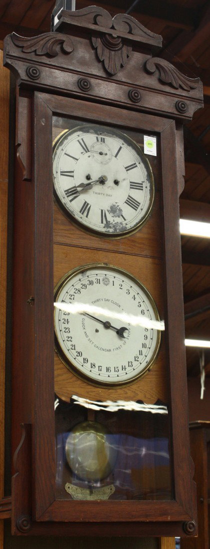 New Haven calendar clock: New Haven thirty day calendar clock, having an oak case with a single door opening to reveal the two original dials, one having Roman numerals the lower with Arabic numerals and marked New Haven, 40''