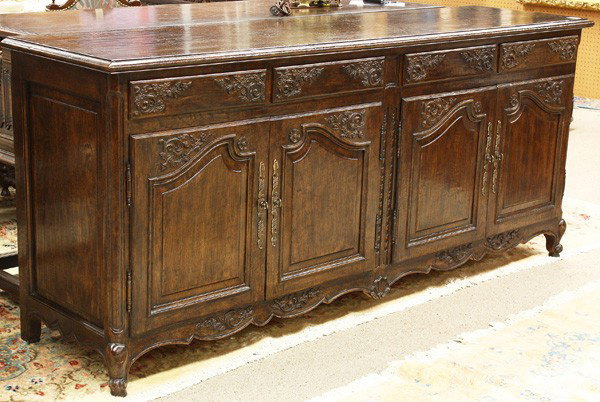 French Provincial style buffet: French Provincial style buffet, executed in oak and having a rectangular top above the panelled and sectioned case each having two drawers above two doors with relief carved reserves, the scalloped to
