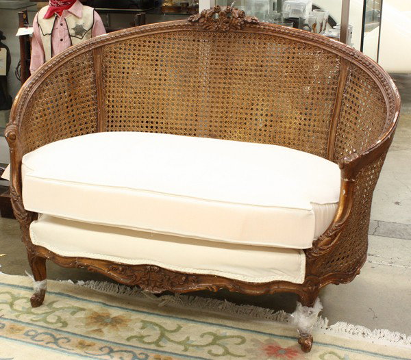 Rococo style settee: Rococo style settee, having a carved floral crest centering the curved caned back continuing to the inswept arms, and rising on cabriole legs, 36''h x 50''w