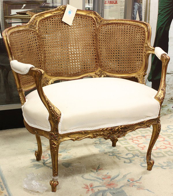 Rococo style settee: Rococo style giltwood carved settee, the cane three section back having relief carved reserves and rising on carved cabriole legs, 33''h x 34''w x 22''d