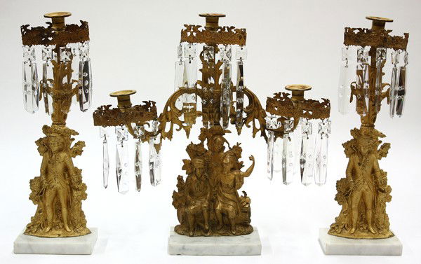 Gilt garniture suite: (Lot of 3) Garniture set, the gilt mantel garniture each having prisms suspended from the oval light surrounds, the bases each with a contrasting model, including a three light Daniel Boone model with