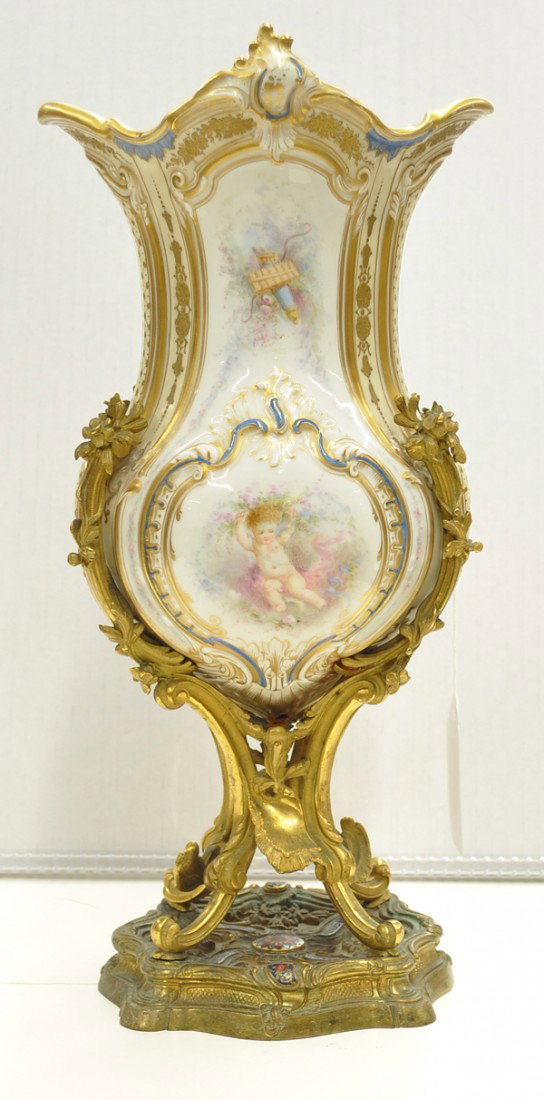 Continental ormolu mounted vase: Continental ormolu mounted footed porcelain vase, the polychrome decorated body with raised gilt accents centering the central medallion depicting playful putti supported by an ormolu gilt bronze moun