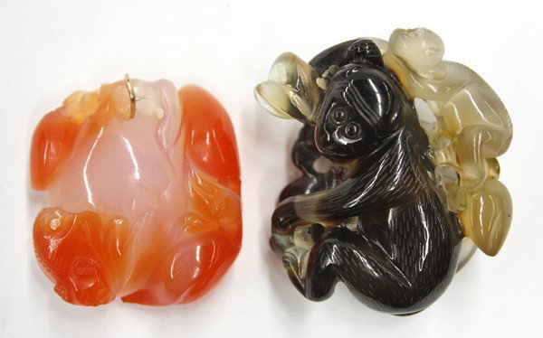 Chinese Stone Toggles, Monkey/Bat: (Lot of 2) Chinese carved stone toggles, the first with the dark areas carved as a large monkey scratching its head surmounted by a small companion of translucent tan color above a fruiting peach spri
