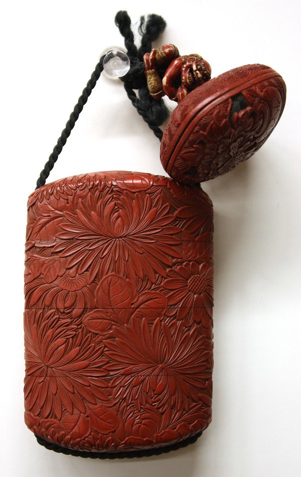 Japanese Cinnabar Lacquer Inro, Edo Period: Japanese cinnabar lacquer (tsuishu) three-case inro, 19th century, the lenticular body finely carved overall with leafy chrysanthemum blossoms, roiro interiors, 3''l; together with a polychromed ivory