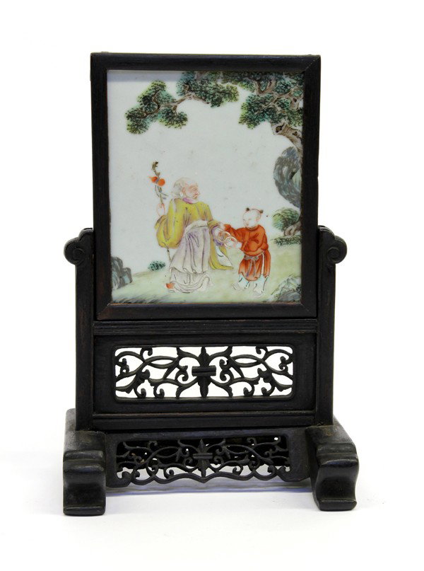 Chinese Table Screen with Porcelain Plaque: Chinese porcelain plaque inset as a small table screen, the polychrome decorated porcelain depicting an elderly sage and young attendant holding linked rings under a gnarled pine, all set within a woo