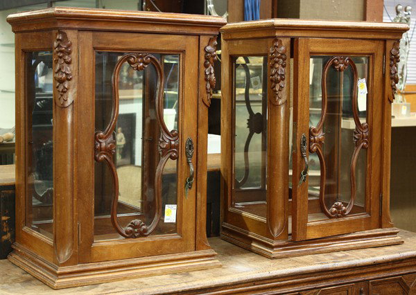 French table vitrines: Pair of French walnut table vitrines, each having a molded crest with fruit carved relief decorated supports, the single door opening to a mirrored interior, and rising on a molded base, 25''h x 18''w