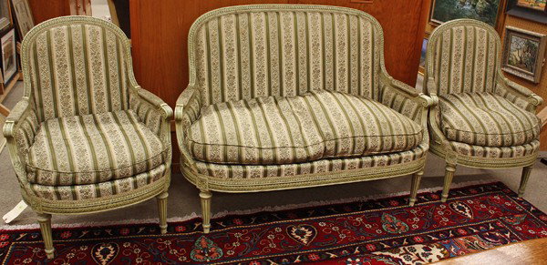 Neoclassical style salon suite: (Lot of 3) Neoclassical style salon suite, each piece having a paint decorated surface, the relief carved crest rail continuing to the padded arms and rising on fluted legs, consisting of a settee 41'