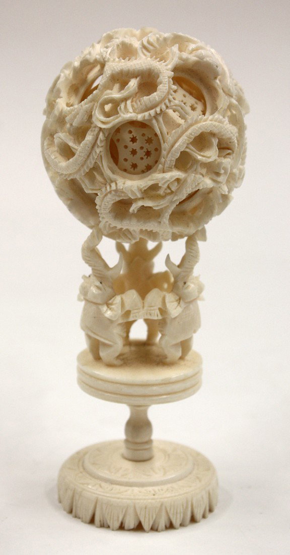 Chinese Ivory Puzzle Ball with Elephant Stand: Chinese ivory puzzle ball and stand, the sphere with at least six reticulated layers and carved with entwined dragons heightened with dark pigment eyes to the outermost layer, together with a pedestal