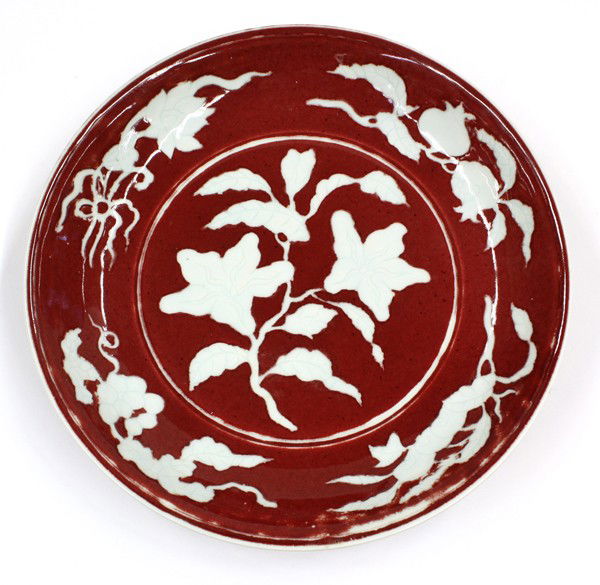 Chinese Underglaze Red Decorated Porcelain Dish: Chinese underglaze red copper decorated porcelain dish, the interior well centered by an incised leaf floral spray of greenish-white hue silhouetted against a deep red ground repeated on the sloping s
