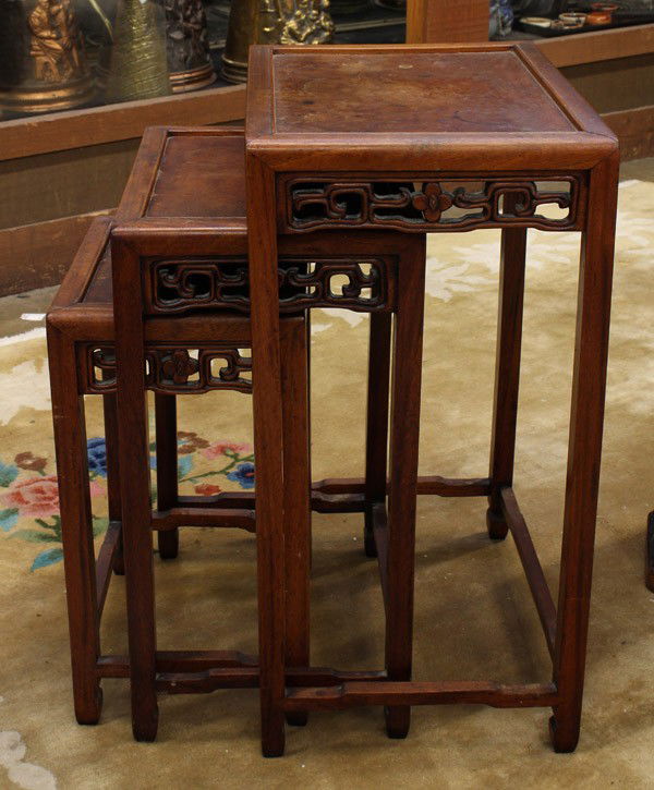 Chinese Nesting Tables: Set of three Chinese wooden nesting tables, each inset with a burlwood floating panel to the top, the apron pierced with flowers bracketed by scrolling tendrils, all raised on slender square supports