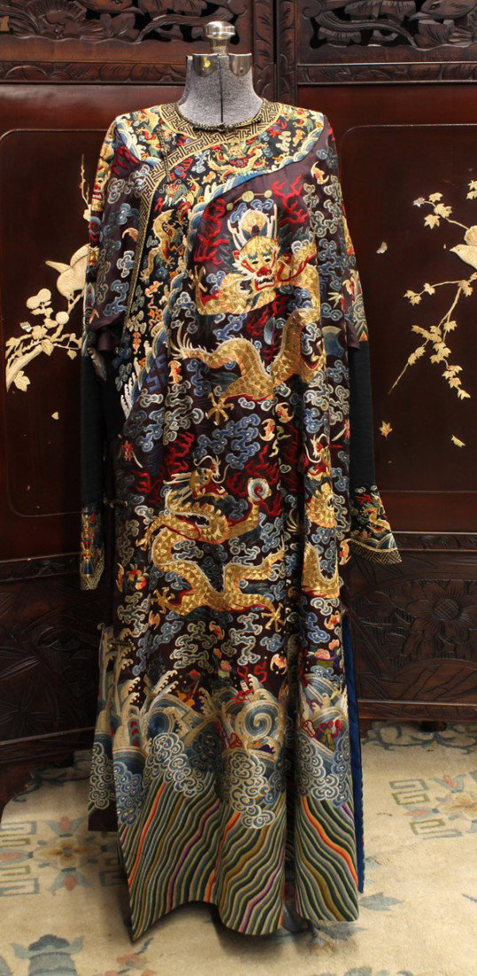 Chinese Theatrical Dragon Robe: Chinese jifu form theatrical dragon robe, featuring nine gilt couched dragons meandering on a blue satin ground accented with color thread embroidered jewels, clouds, bats, shou medallions and auspici