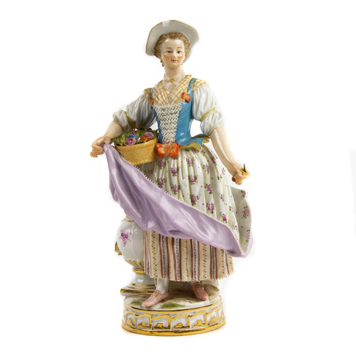 A Meissen figure of a lady with basket of flowers, late 19th century: A Meissen figure of a lady with basket of flowers, late 19th century, modeled holding a basket of flowers, raised on a gilt highlighted running band base, underglaze crossed swords with a dot between 