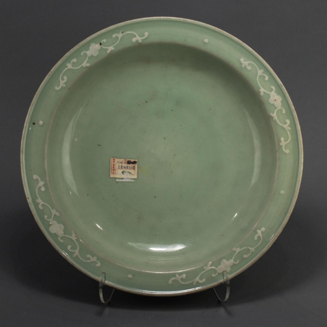 Chinese celadon glazed and white slip decorated charger: Chinese celadon glazed and white slip decorated charger, covered in an overall light pea-green colored glaze, the underside painted in white with prunus, orchid, bamboo, and chrysanthemum, 15.875"dia.