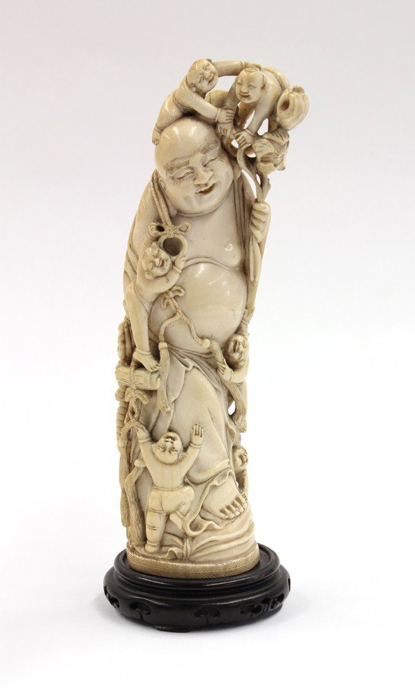 Chinese Ivory Figure, Budai and Children: Chinese ivory carving of Budai and children, the standing Buddhist deity sculpted with a joyous smile while six children climb mischievously onto him and tug at his garments, two other youngsters on h