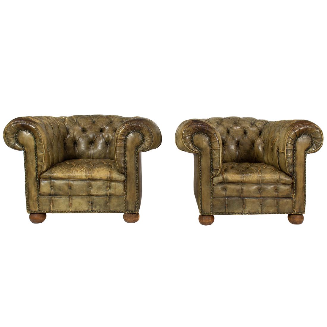 Chesterfield, Armchairs, pair: Chesterfield, Armchairs, pair upholstered in olive leather with outscrolled arms, the fronts with brass nail head trim, and rising on compressed bun feet, 33"h x 43"w x 36"d
