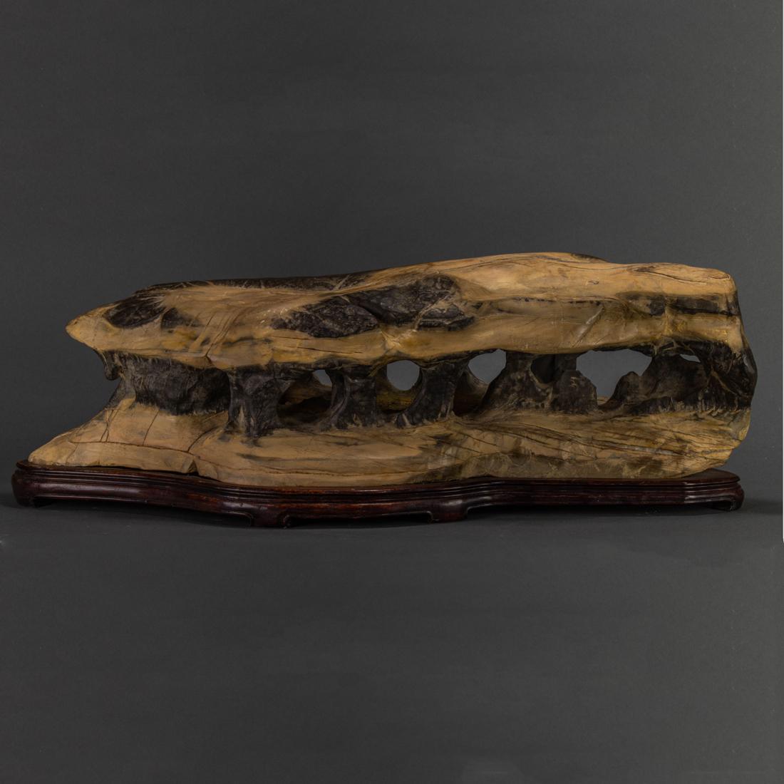 Chinese gray and beige limestone scholar's rock: Chinese gray and beige limestone scholar's rock, arranged horizontally to depict a labyrinth of grottos, Northern style wood stand, width 24".
